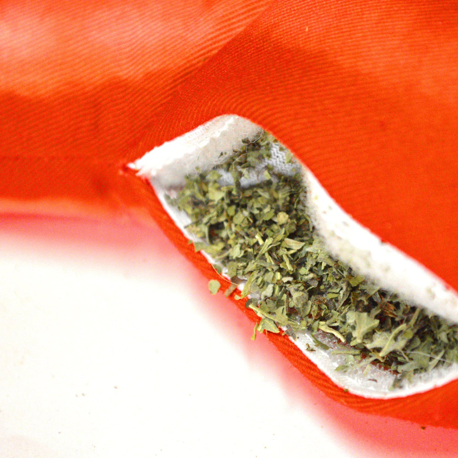 Close-up of the chili pepper toy's refillable pocket, showing loose catnip inside a zippered opening on the red fabric.