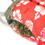 Close-up of a sloth toy's red Hawaiian shirt with a pocket filled with dried catnip, showing a textured, leafy green mixture inside.