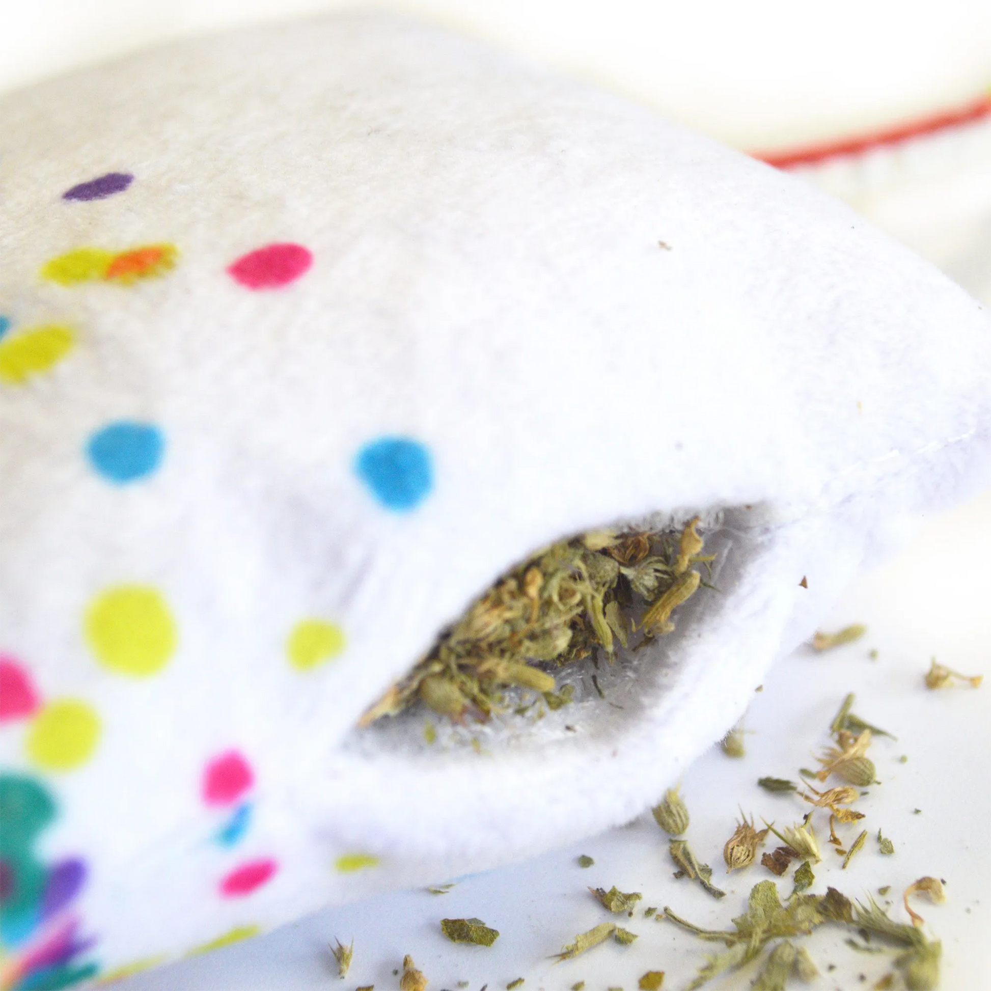 Close-up of the cupcake toy's refillable catnip pocket with visible premium catnip spilling out.