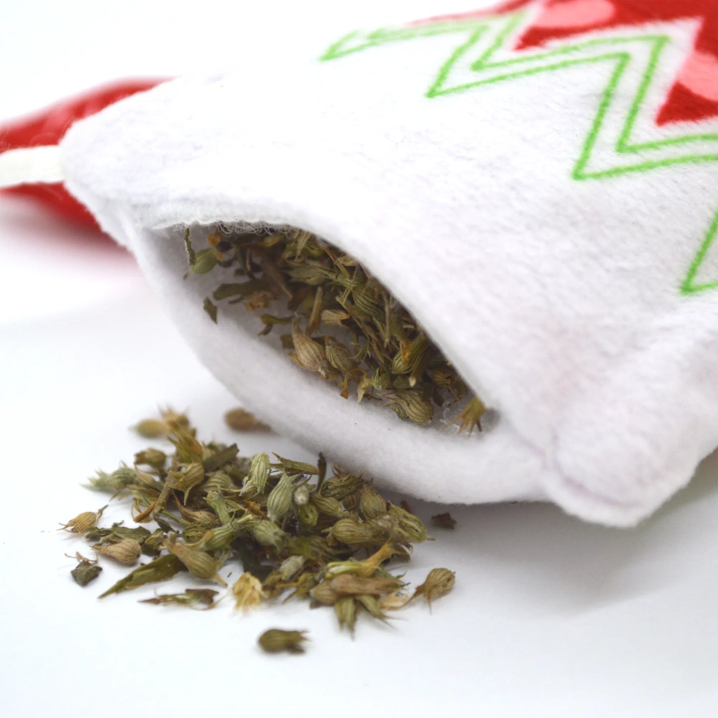 A white and red holiday stocking cat toy partially open, showing the premium catnip contents spilling out.