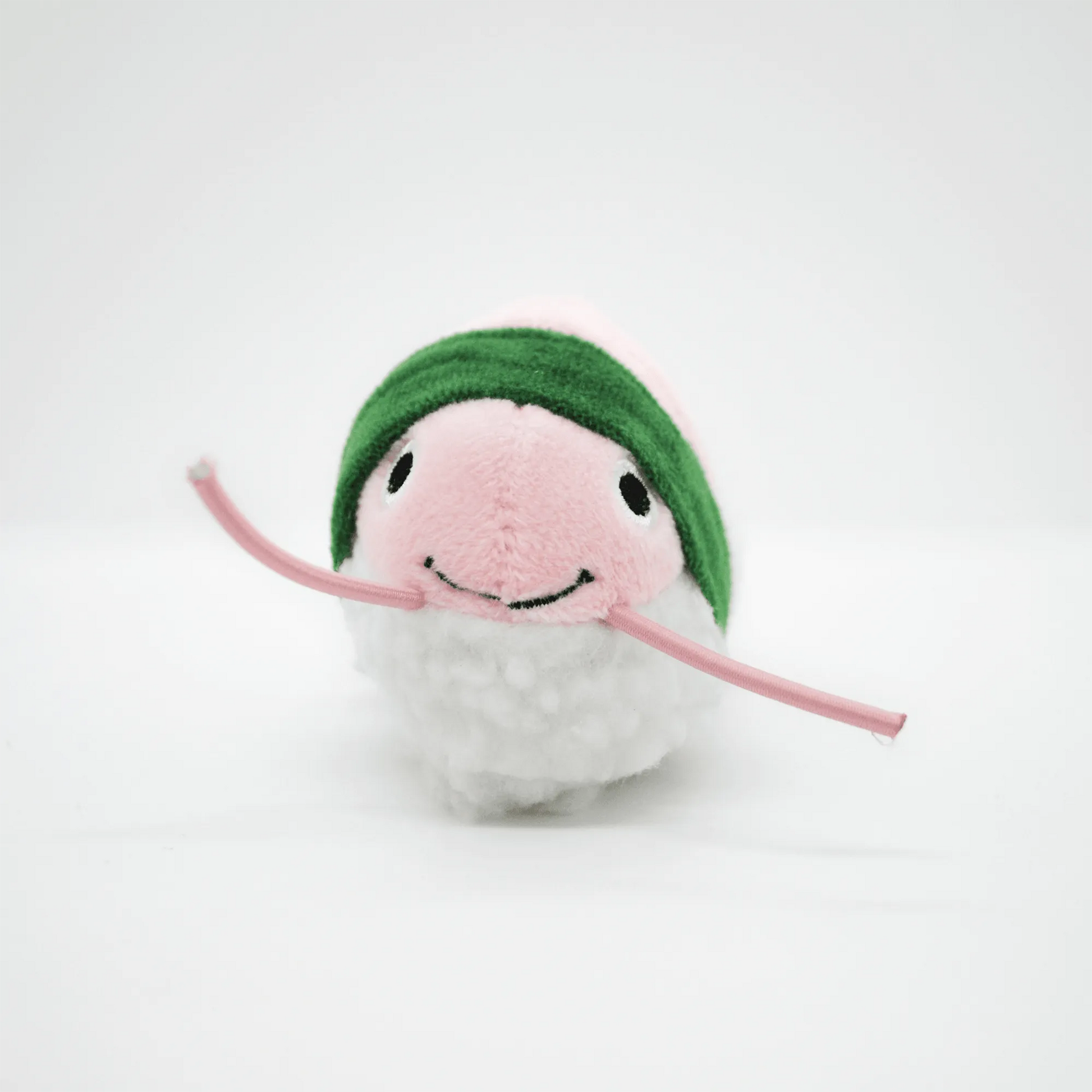 Front view of the pink shrimp roll toy with a smiling face and green band.