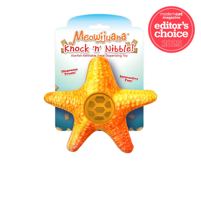 A bright orange starfish-shaped treat dispenser toy for cats, labeled "Meowijuana Knock 'n' Nibble," designed for interactive play.